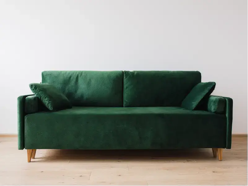 Grünes Sofa auf Holzboden – Beispiel für ein professionell gereinigtes Polstermöbelstück.